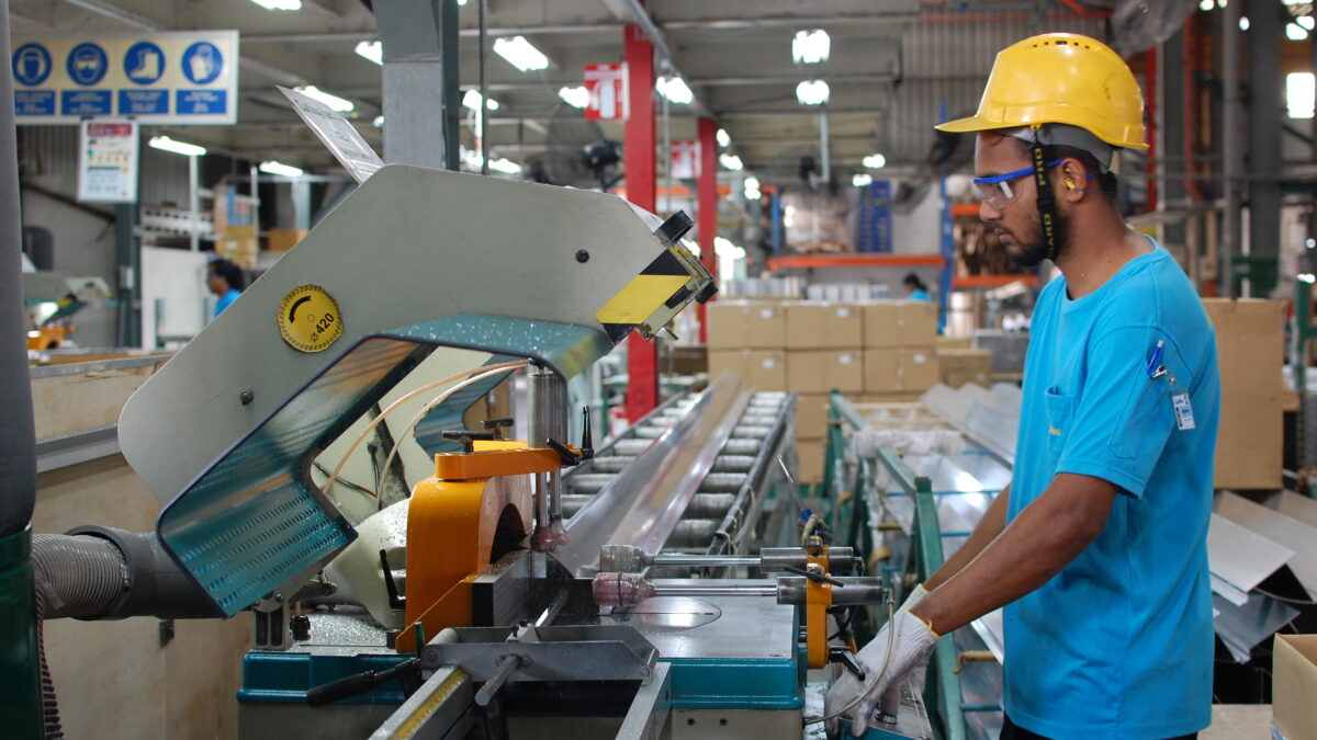 A worker operating precision cutting machinery for aluminium extrusion profiles in a manufacturing facility, where anodizing aluminium processes enhance the material’s durability and appearance.
